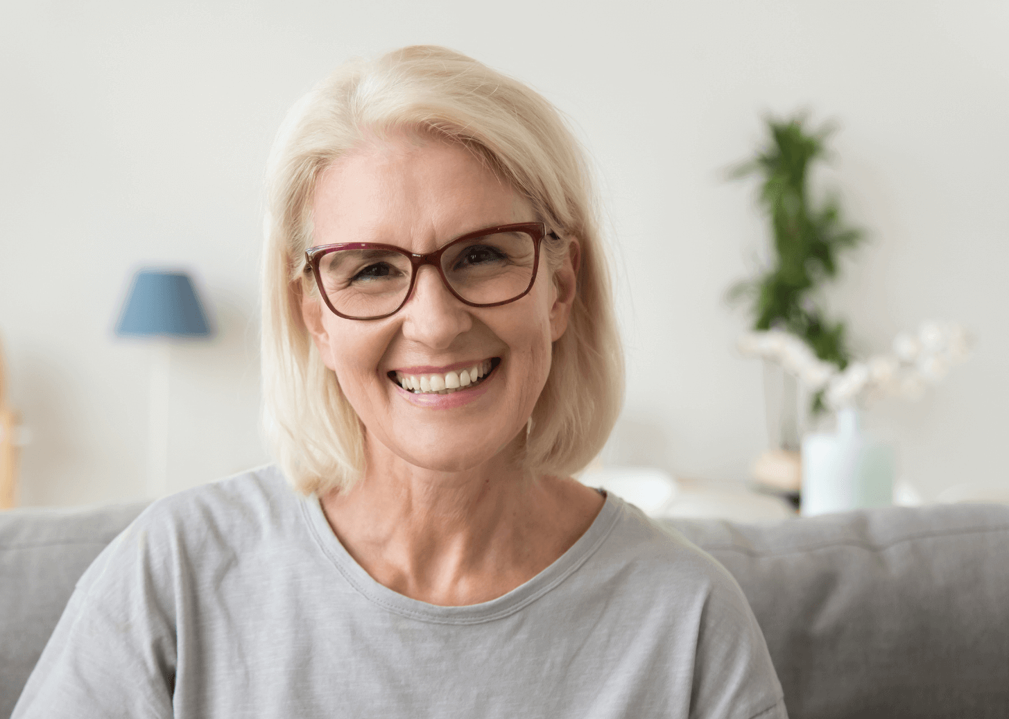 Lady with glasses smiling with her new smile thanks to dental implants