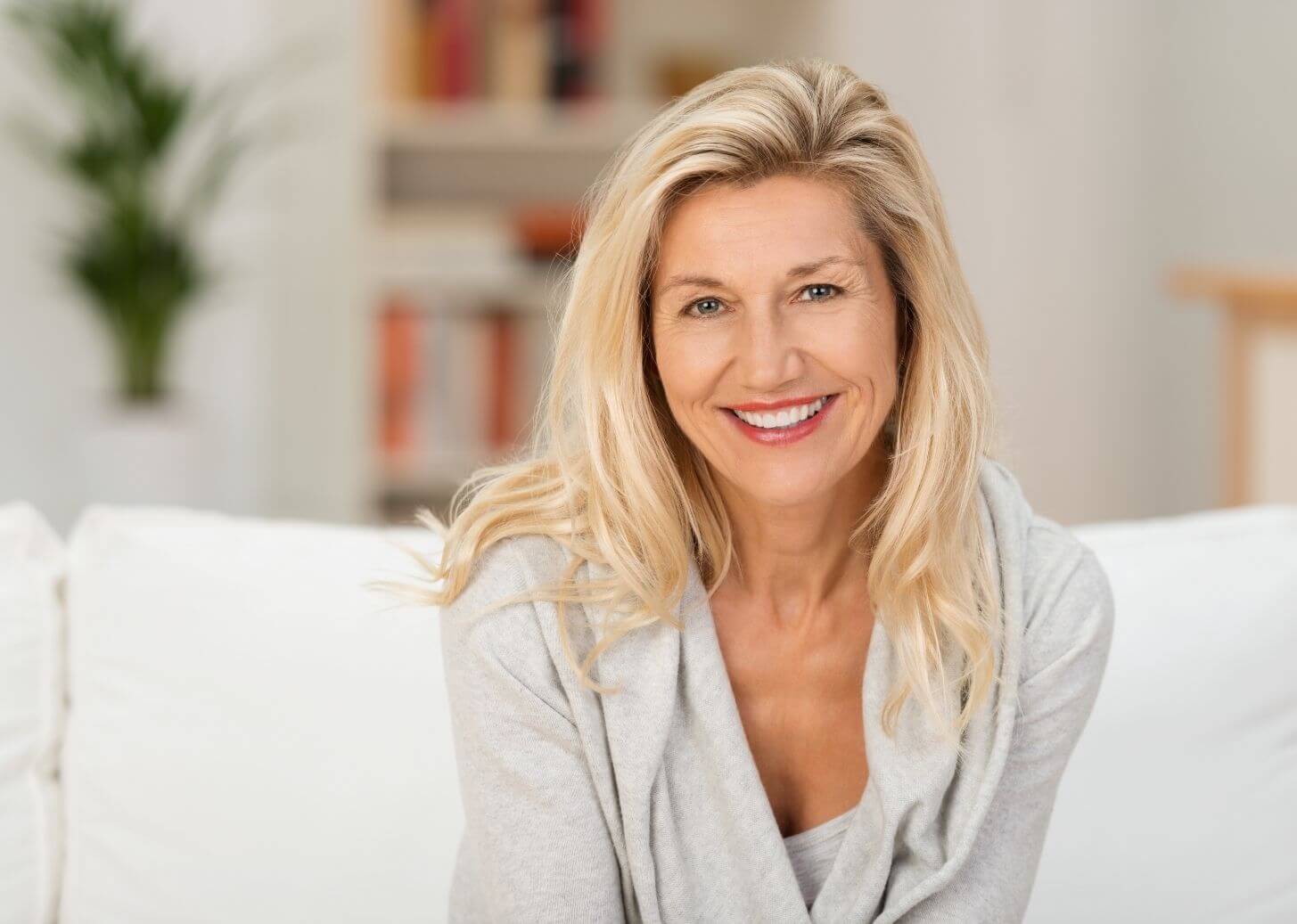 Mid age woman smiling whilst sitting on the sofa