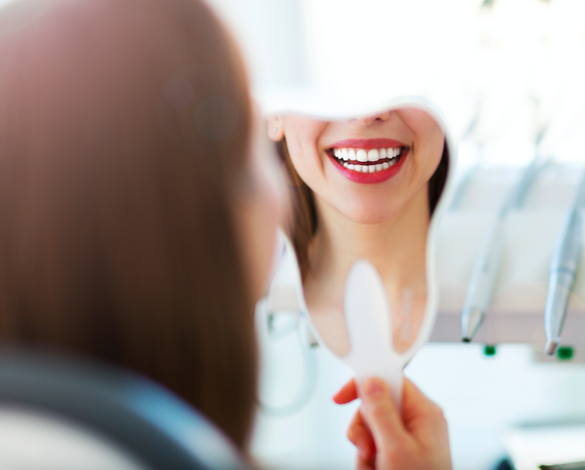 Lady seeing her teeth whitening results in mirror after in-surgery whitening at The Town House Dental Practice