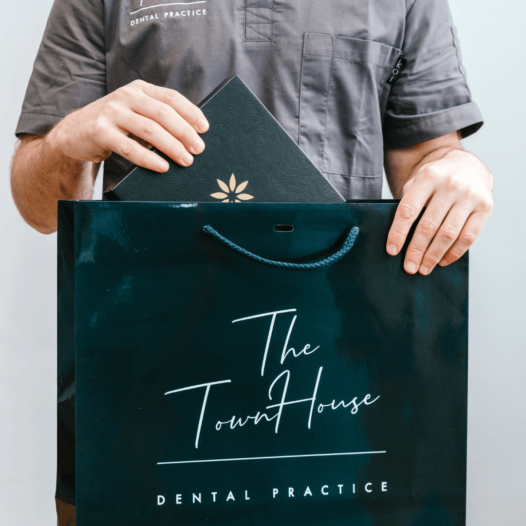 The Town House Dentist putting Invisalign package into a blue Town House Dental Practice branded bag.