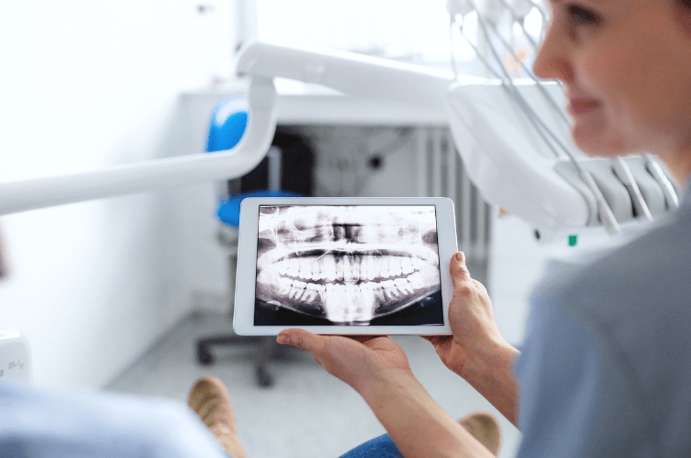 Dentist holding image of x-ray for patient to show their scans.